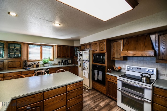 kitchen with a textured ceiling, dark hardwood / wood-style flooring, black appliances, custom range hood, and decorative backsplash