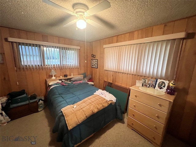 bedroom featuring ceiling fan, light colored carpet, wooden walls, and a textured ceiling