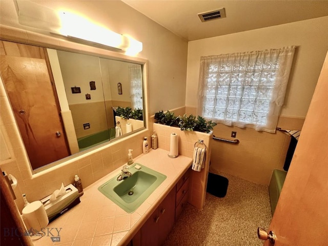805 E Orr St, Dillon, MT 59725 - bathroom featuring tile walls, visible vents, walk in shower, vanity, and wainscoting