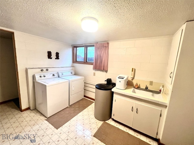 washroom with a textured ceiling, washer and dryer, and sink