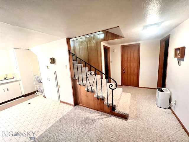 stairway featuring a textured ceiling and carpet