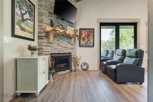 living room with a stone fireplace and light hardwood / wood-style floors