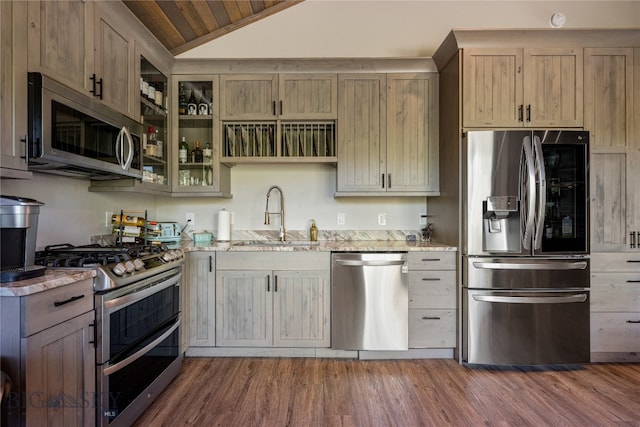 kitchen featuring light stone counters, lofted ceiling, stainless steel appliances, and sink