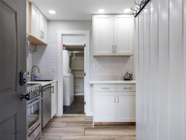 kitchen with white cabinetry, sink, stainless steel appliances, tasteful backsplash, and washer / dryer