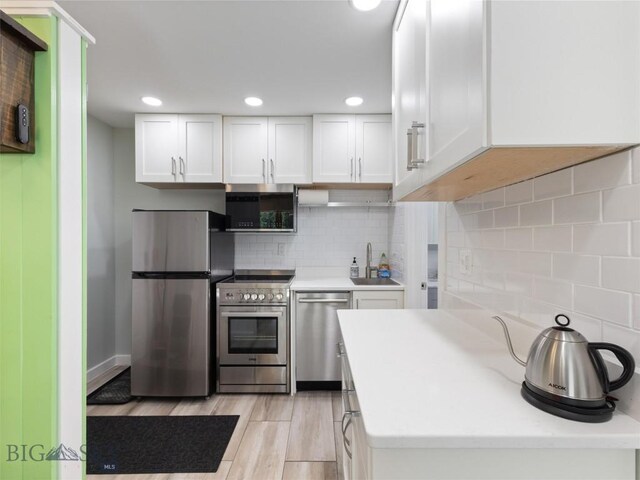 kitchen featuring appliances with stainless steel finishes, tasteful backsplash, and white cabinetry