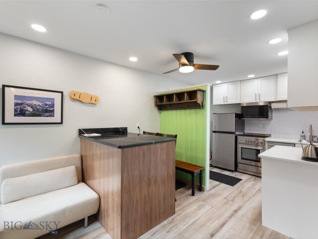 kitchen with ceiling fan, stainless steel appliances, backsplash, kitchen peninsula, and white cabinets