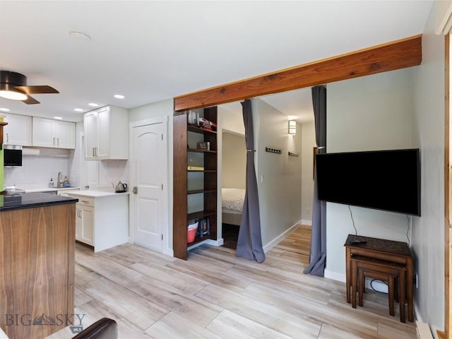 kitchen featuring tasteful backsplash, white cabinetry, ceiling fan, and light hardwood / wood-style flooring