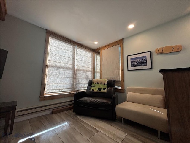 sitting room featuring a baseboard heating unit, recessed lighting, and wood finished floors