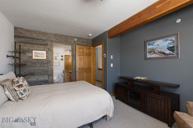 carpeted bedroom featuring connected bathroom and wood walls