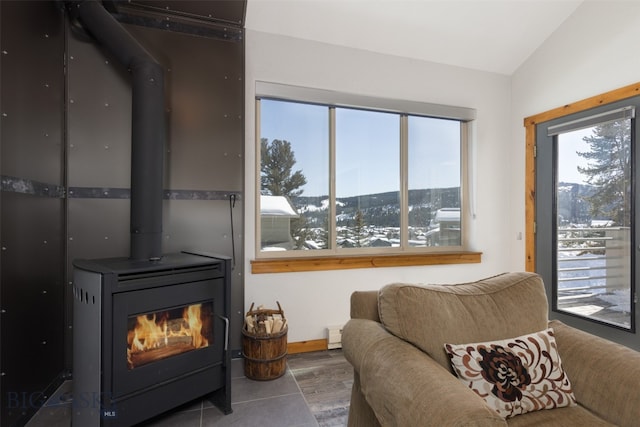 sitting room with vaulted ceiling, hardwood / wood-style floors, and a wood stove