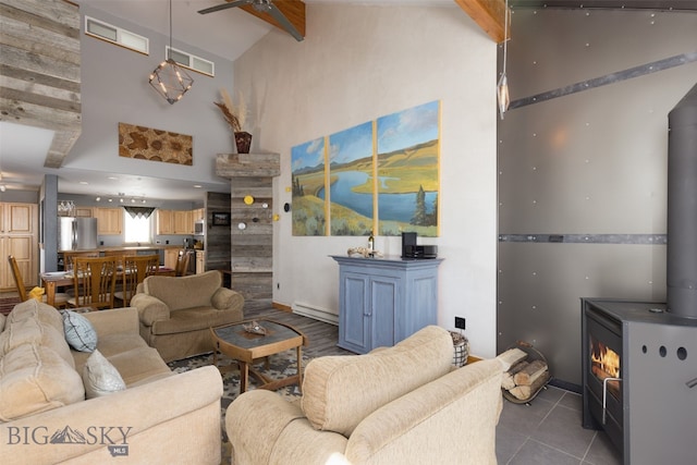 tiled living room featuring a wood stove, a baseboard radiator, ceiling fan, and a high ceiling