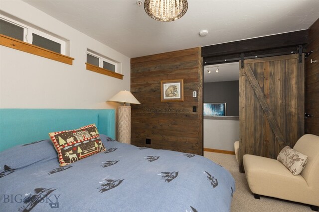 carpeted bedroom featuring wood walls and a barn door