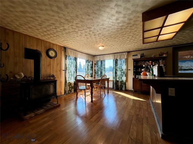 rec room with hardwood / wood-style floors, wood walls, and a wood stove