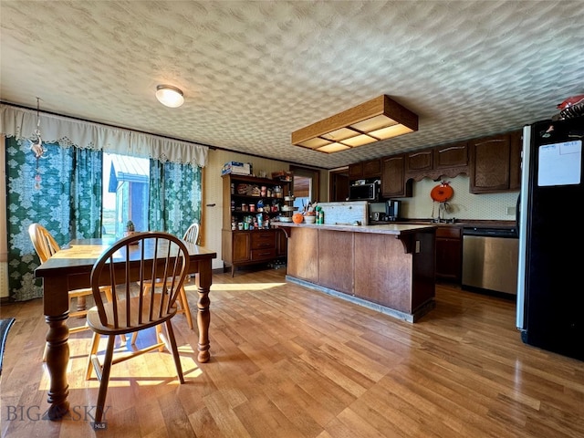 kitchen featuring light hardwood / wood-style flooring, stainless steel dishwasher, refrigerator, a textured ceiling, and dark brown cabinets