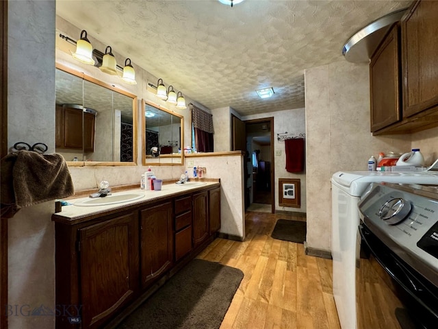 bathroom featuring washing machine and dryer, hardwood / wood-style floors, vanity, and a textured ceiling