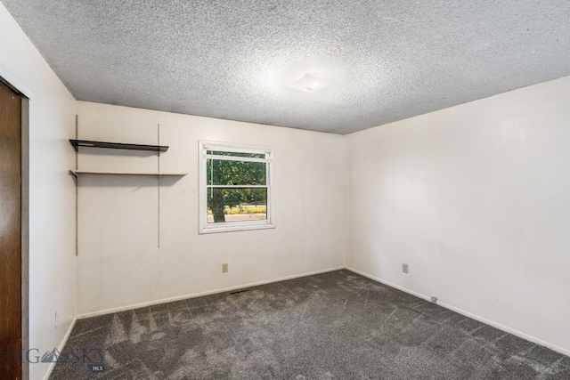 carpeted empty room featuring a textured ceiling