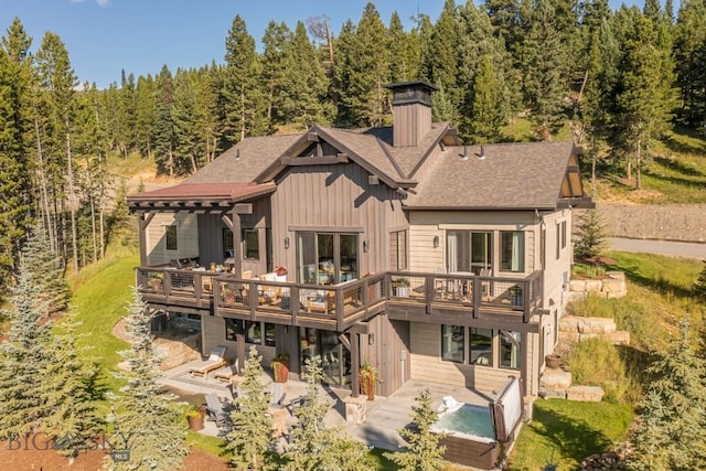 56 Outlook Trl, Big Sky, MT 59716 - rear view of property with a chimney, a deck, a patio area, a view of trees, and a shingled roof