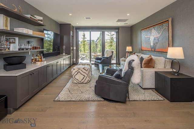 living room featuring light wood-type flooring and a wall of windows