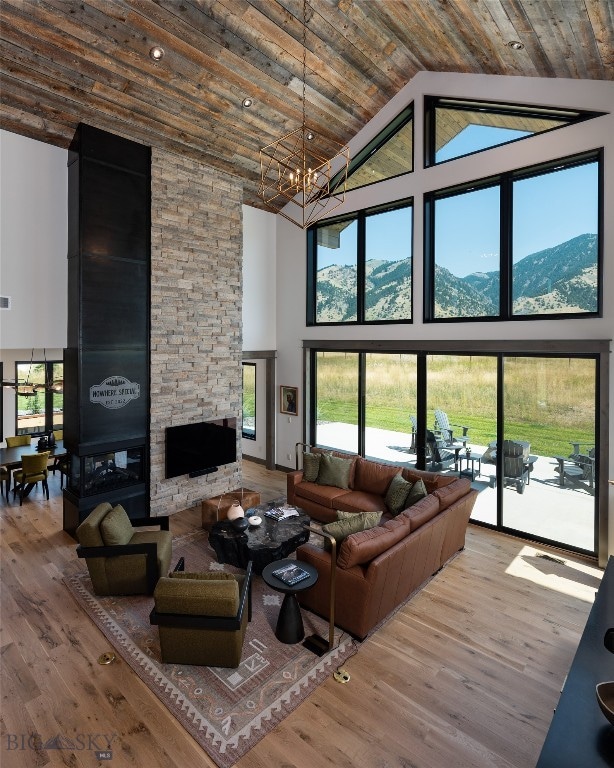 living room featuring a mountain view, hardwood / wood-style floors, a stone fireplace, and high vaulted ceiling