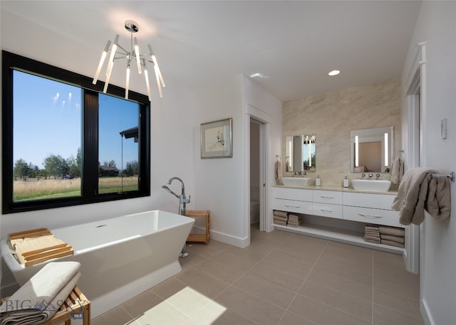 bathroom with tile patterned flooring, a tub to relax in, vanity, and an inviting chandelier