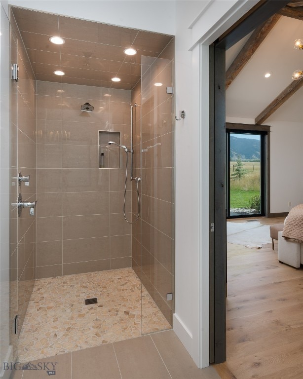 bathroom featuring beam ceiling and walk in shower