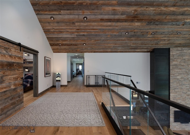 hallway featuring hardwood / wood-style floors, a towering ceiling, and a barn door