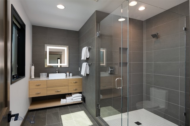 bathroom with vanity, an enclosed shower, and tile walls