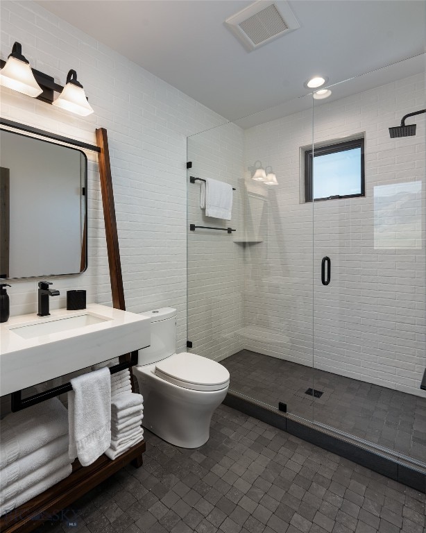 bathroom with toilet, a shower with shower door, and sink