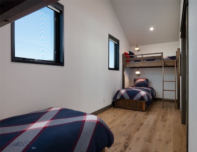 bedroom with vaulted ceiling, multiple windows, and light wood-type flooring