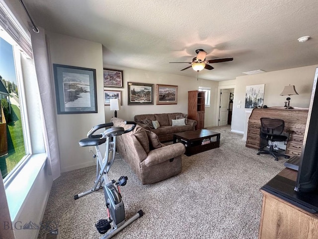 carpeted living area featuring baseboards, visible vents, a textured ceiling, and ceiling fan