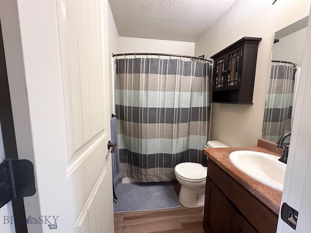 bathroom with a shower with curtain, toilet, a textured ceiling, wood finished floors, and vanity