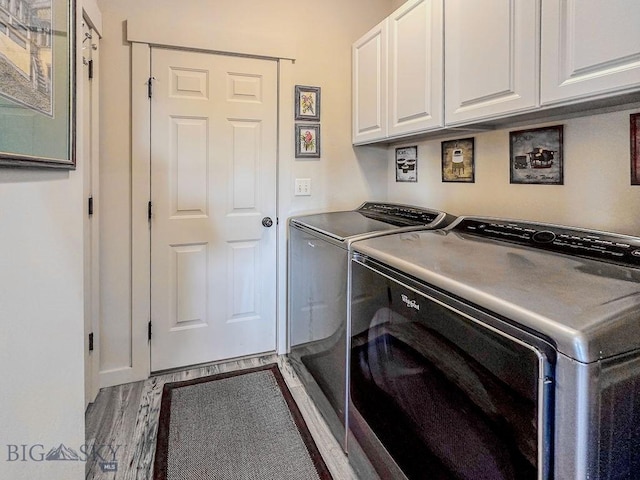 clothes washing area featuring separate washer and dryer, wood finished floors, and cabinet space