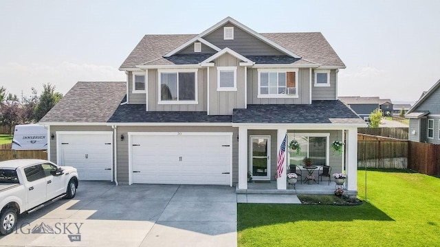 view of front of home with a front yard, fence, concrete driveway, a garage, and board and batten siding