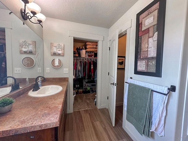 bathroom featuring vanity, a textured ceiling, a walk in closet, and wood finished floors