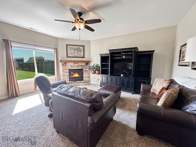 carpeted living room featuring visible vents, baseboards, a fireplace, a textured ceiling, and a ceiling fan