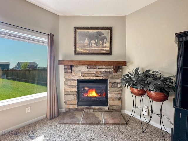 interior details with a stone fireplace, carpet flooring, and baseboards