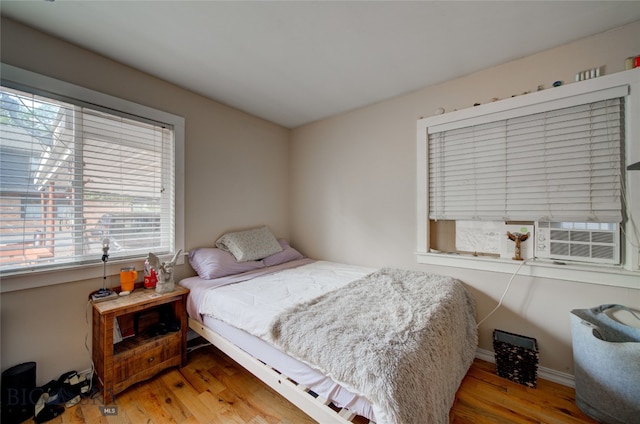 bedroom with cooling unit and light hardwood / wood-style flooring