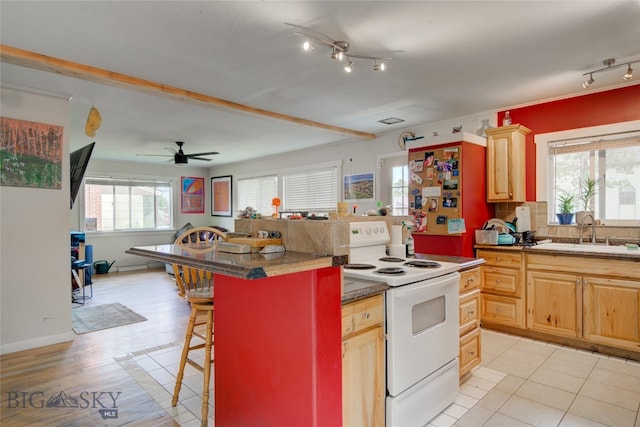 kitchen featuring a healthy amount of sunlight, white range with electric cooktop, sink, and a kitchen breakfast bar