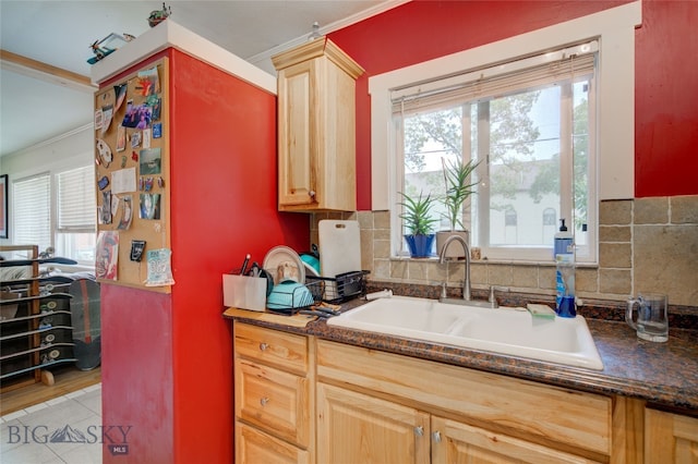 kitchen featuring crown molding, dark stone counters, a wealth of natural light, and sink