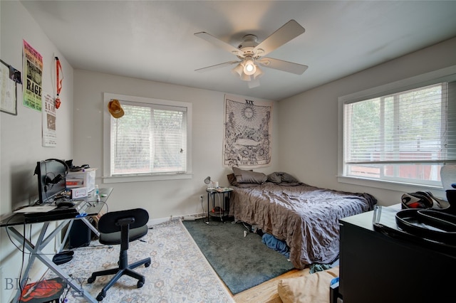 bedroom featuring ceiling fan, hardwood / wood-style floors, and multiple windows