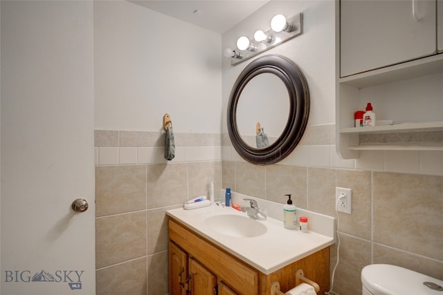 bathroom featuring vanity, toilet, and tile walls