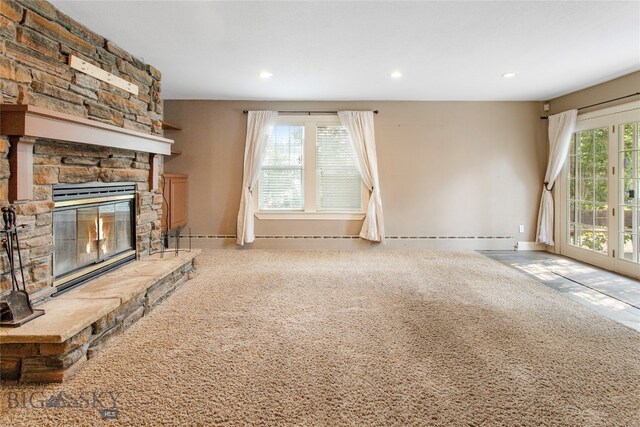 unfurnished living room featuring light colored carpet, baseboard heating, and a fireplace