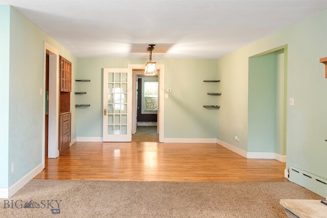 empty room featuring french doors, a baseboard heating unit, and light hardwood / wood-style flooring