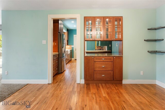 kitchen featuring stainless steel refrigerator with ice dispenser, light wood-type flooring, and light stone countertops