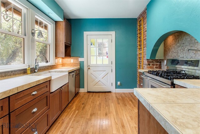 kitchen with backsplash, stainless steel appliances, sink, and light hardwood / wood-style flooring