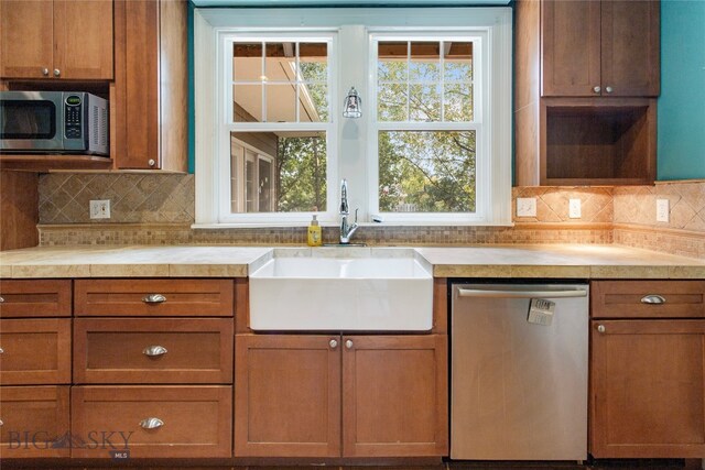 kitchen featuring a healthy amount of sunlight, backsplash, stainless steel appliances, and sink