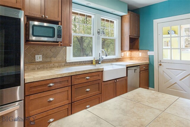 kitchen featuring tile patterned flooring, sink, tile countertops, and appliances with stainless steel finishes