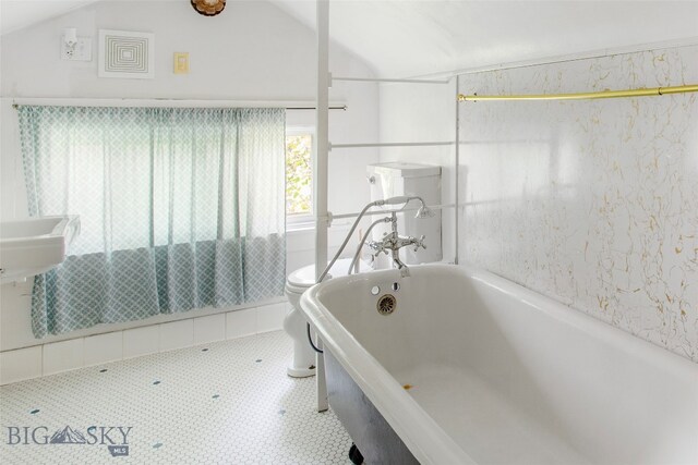 bathroom featuring a tub to relax in, vaulted ceiling, toilet, and tile patterned flooring