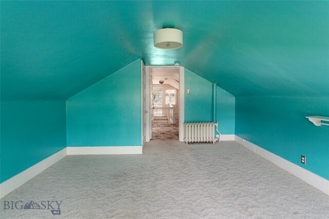 bonus room with radiator, vaulted ceiling, and carpet flooring