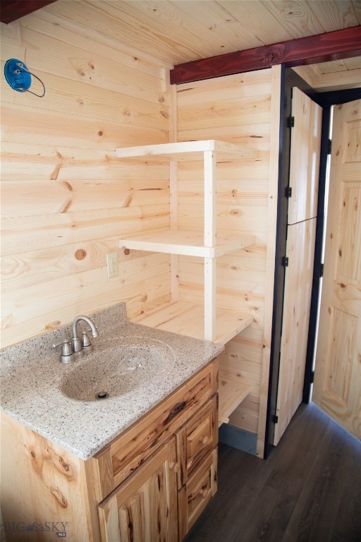 bathroom featuring vanity, wood-type flooring, wood walls, and beam ceiling